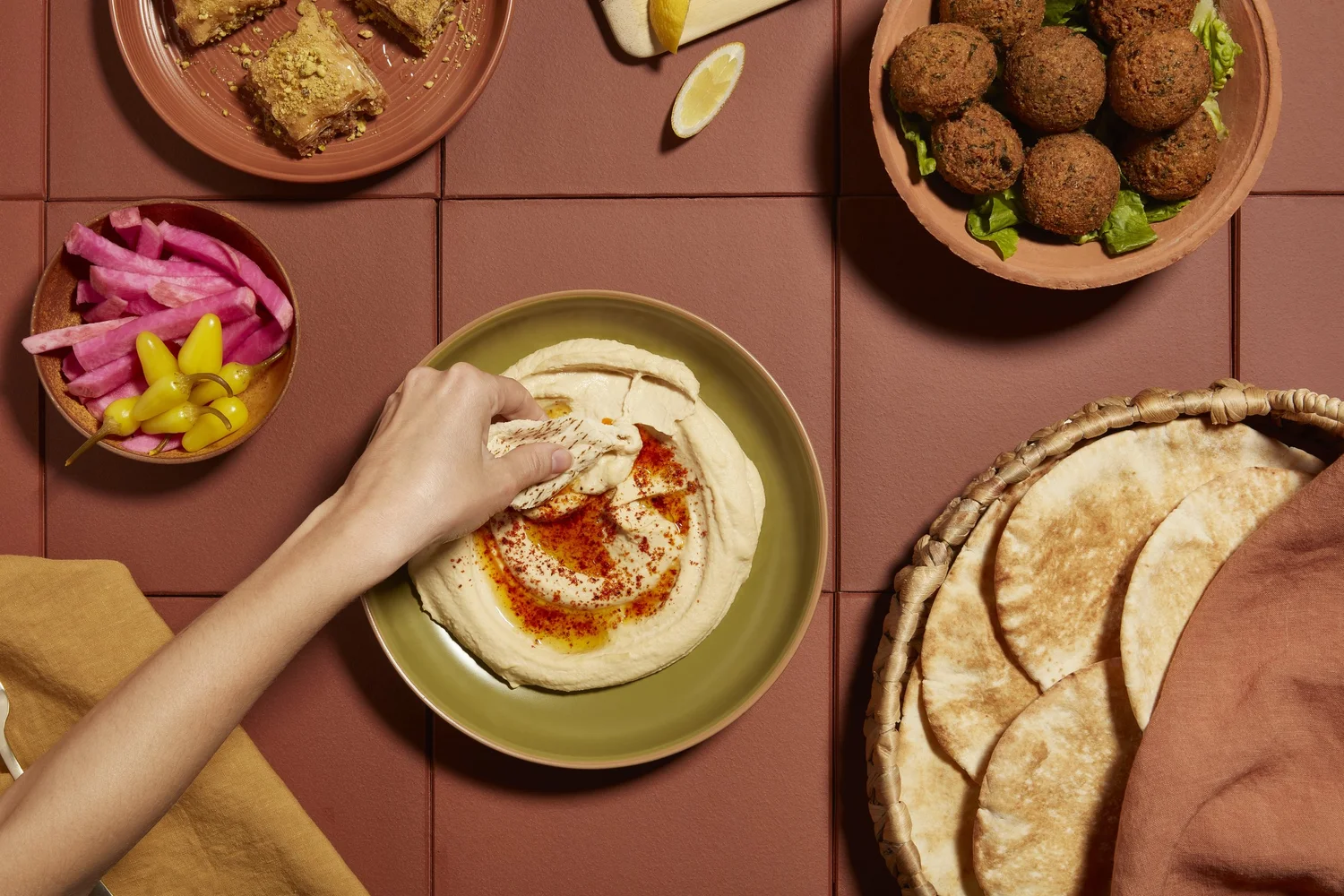 Hand dipping pita into hummus